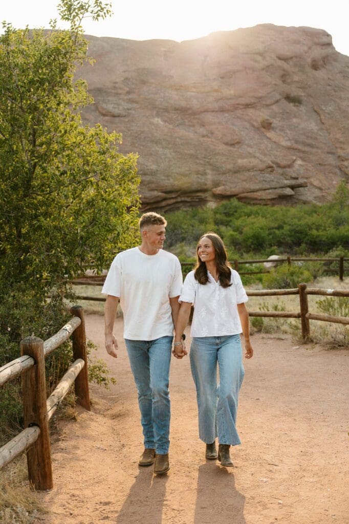 Jordan and Andrew walking hand in hand at Red Rocks during their golden hour engagement session