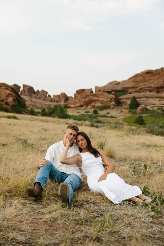 Jordan and Andrew sitting together in a grassy field with red rock formations behind them