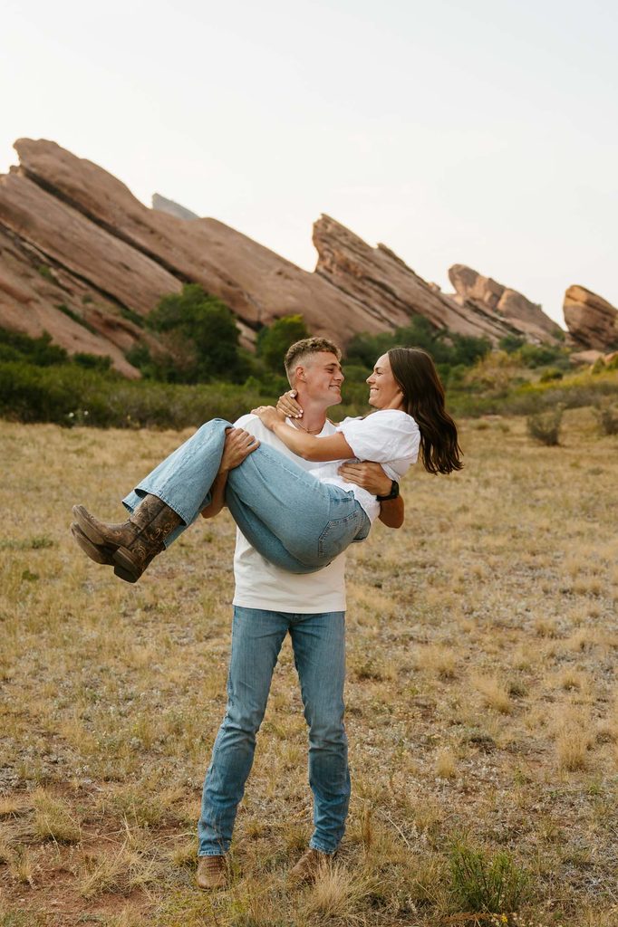 Jordan and Andrew laughing together with the red rock formations behind them during their engagement session