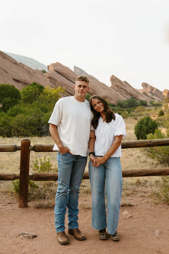 Jordan and Andrew standing together in front of the red rock formations during their Red Rocks engagement session