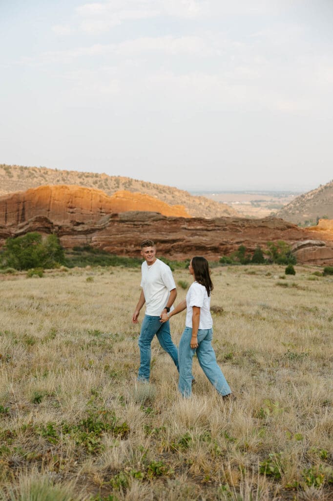 Jordan and Andrew walking together through a field with Red Rocks in the background